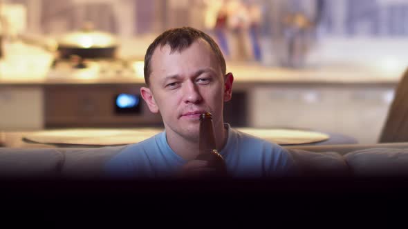 Lonely Man Drinking Beer From a Bottle, Sitting at Home on the Sofa and Watching TV, Camera Movement