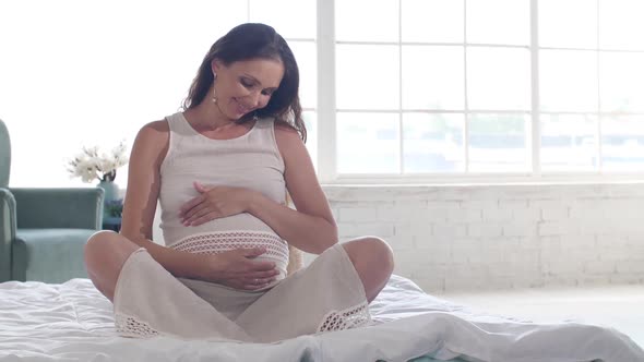 ベッドの上の妊婦は彼女の腹を撫でる / Videohive, Stock footage, People