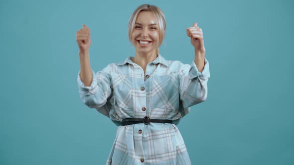 Surprised and Excited Young Woman Enjoys Victory Raises Her Hand Smiles Broadly