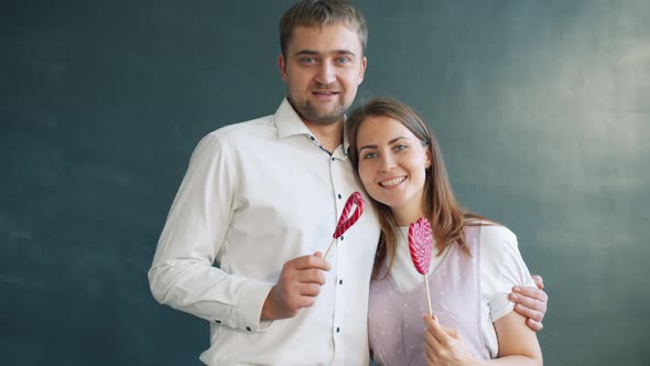 Portrait of Beautiful Couple Holding Heart Shape Lollipops on Valentine's Day