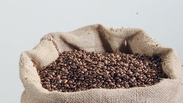 slow motion of coffee beans falling into a burlap sack