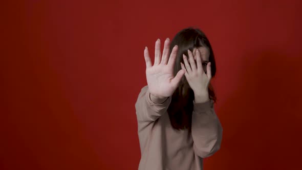 Portrait of Confused Girl in Checkered Shirt Covering Eyes with Hand and Showing Stop Gesture