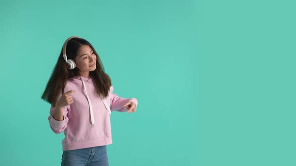 Cheerful Asian Girl in Headphones Moving to Music