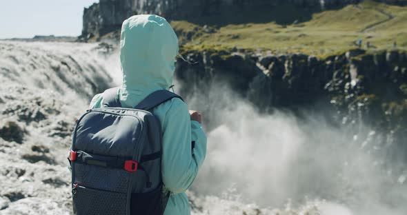 Rear View of a Woman Standing at the Cliff Edge Looking at Detifoss Waterfall in Iceland