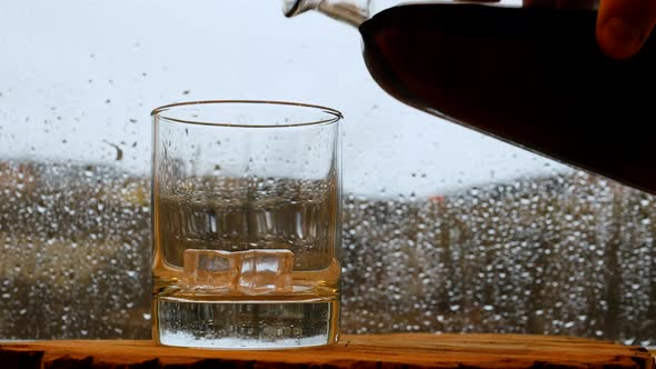 Whiskey On The Bar In The Rain Window. Pour Whiskey At The Bar. A Glass Of Whiskey With Ice