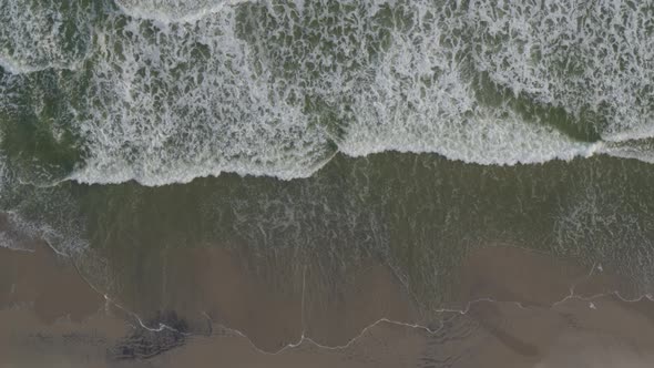 Aerial of frothy waves reaching beach