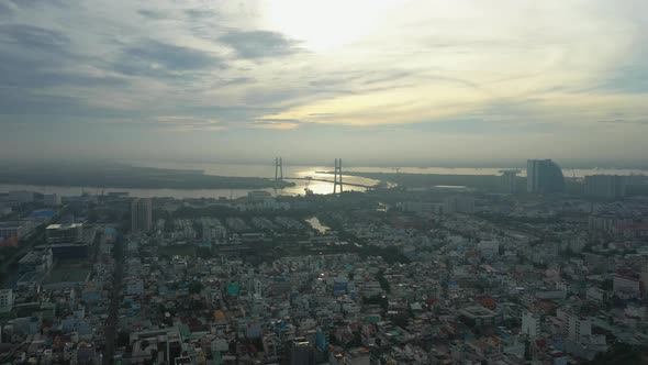 Fly in over urban area towards river and large modern suspension bridge in early morning light part