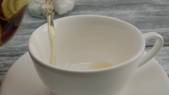 Pouring Black Tea Into a Classic White Cup on a Saucer