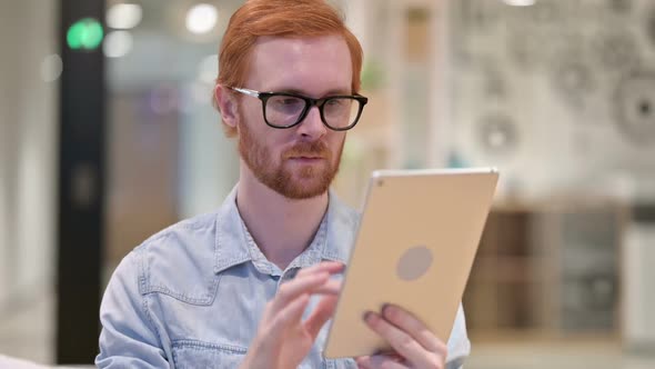 Attractive Young Redhead Man Using Digital Tablet