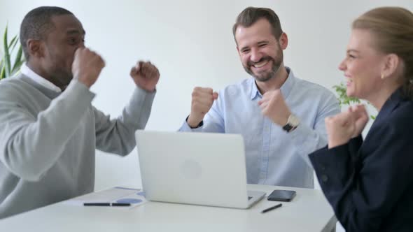 Cheerful Business People Celebrating Success While Using Laptop in Office