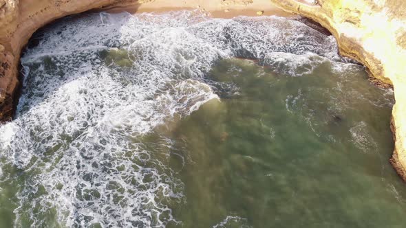 Waves washing on cliff.  Aerial reveal of Carvoeiro coastline. Tilt up shot