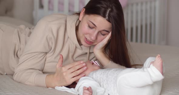 Mom Lies On The Bed With The Baby, Gently Strokes His Face And Tells Something