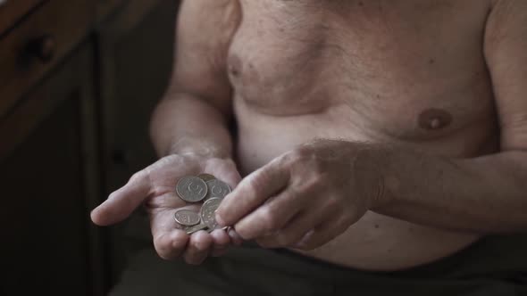 Poor Elderly Man Counting Coins in a Hand