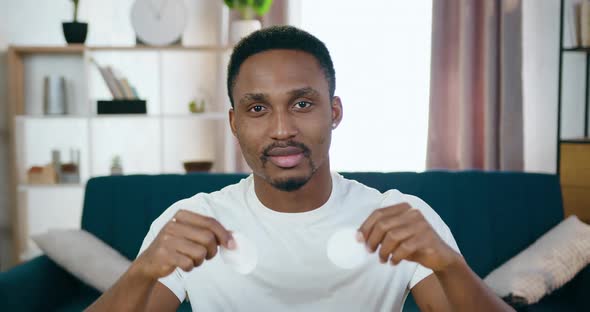 Young Black-Skinned Guy Sitting in front of Camera and Presenting Cotton Pads for Cleansing