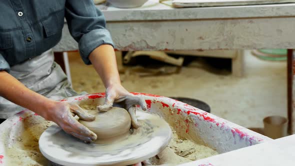 Mid section of female potter molding clay 