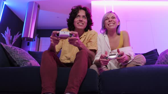 Smiling Couple Holding Gamepads Playing Video Game at Home. Low Angle Shot of Young People Spending