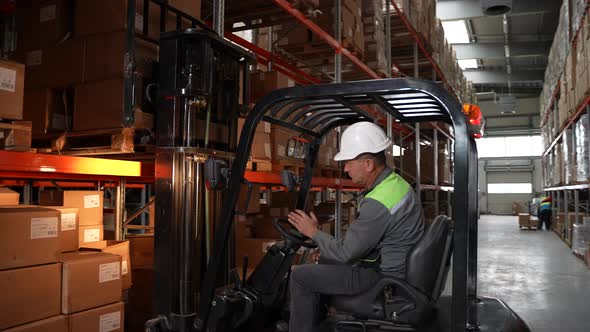 Forklift Truck Operator During Work in Storehouse