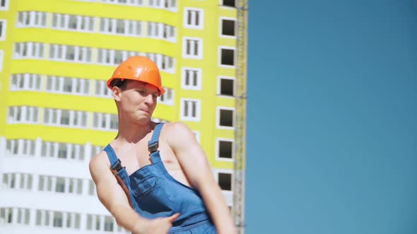 Happy Caucasian Man Builder in Hard Hat Dancing. Worker Funny Moves Background Construction Site.