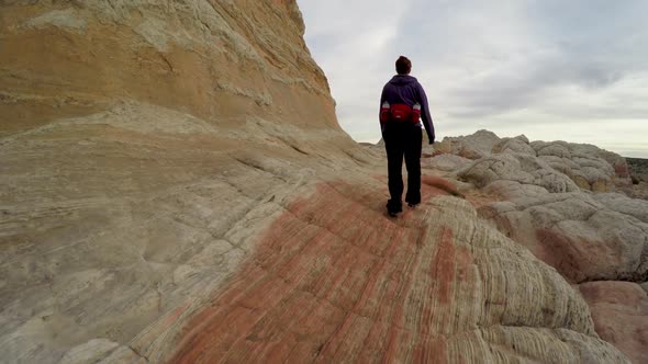 Following woman hiking through White Pocket