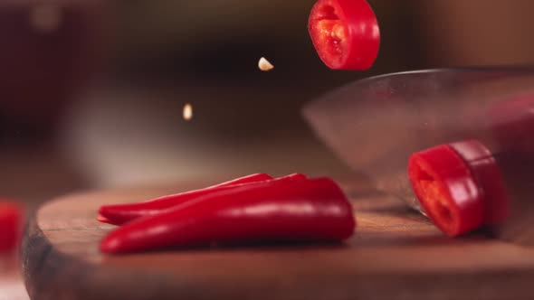 Knife Cutting Red Chilli Pepper on Wood in Slow Motion