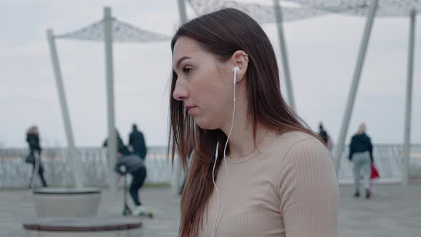 Caucasian Beautiful Female in Headphones Sitting in Terrace Drink Coffee and Listening to Music