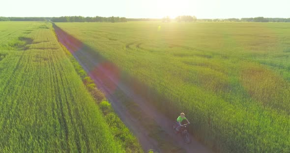 Aerial View on Young Boy, That Rides a Bicycle Thru a Wheat Grass Field on the Old Rural Road