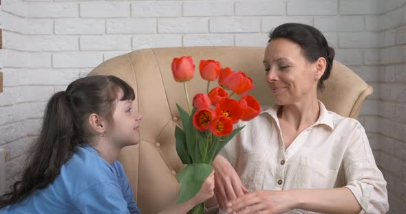 The child gives flowers to mom.