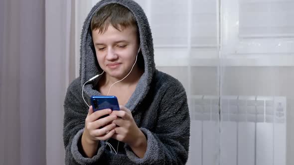 Carefree Child Dances Joyfully Listens to Music on Headphones Using a Smartphone