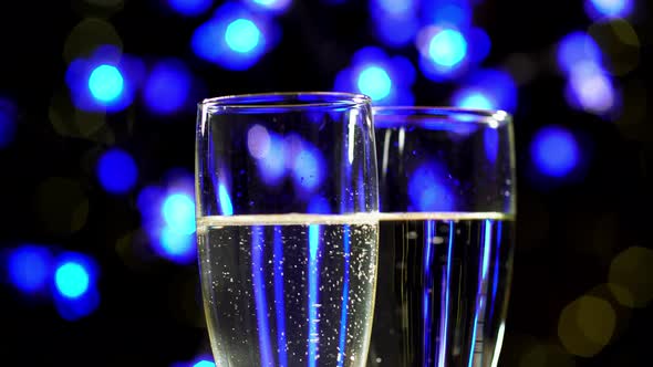 Two Wine Glass Full of Sparkling Wine on Blue Bokeh Background