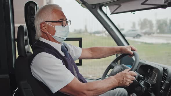 Portrait of Senior Bus Driver in Face Mask at Driver Seat