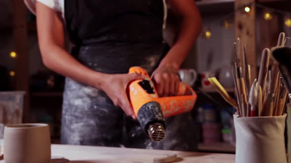 Pottery in the Studio  Woman Potter Burns Clay Handle Using an Industrial Dryer