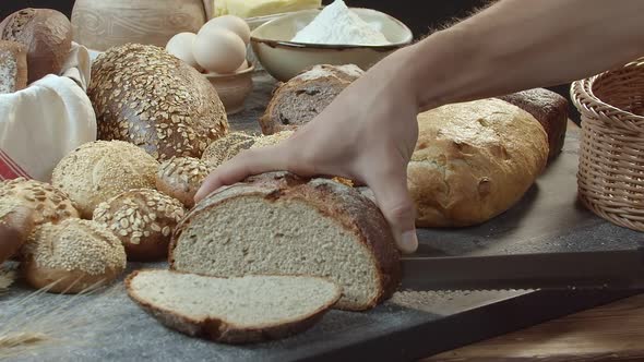 Hands Cutting the Baked Dutch Bread on the Table