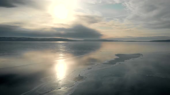 It's an Aerial View. The Winter Landscape of the Freezing River. The Ice Reflects the Sky and the