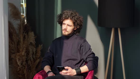 Man Sitting Near Window and Writing a Sms on Background of Sunset