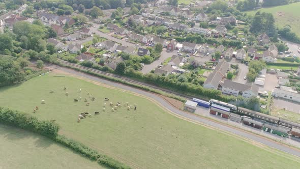 Stationary wide aerial shot Village of Washford, Somerset in the background, with a diesel train lea