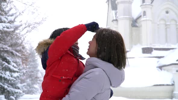 Asian Mother And Son Enjoying Snowy Winter Day Outdoors