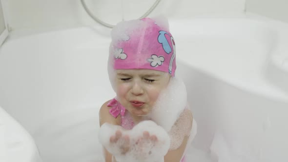 Cute Blonde Girl Takes a Bath in Swimwear. Little Child Washes Her Head