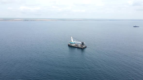 Cargo Ship with a Crane is at Sea Far From the Shore