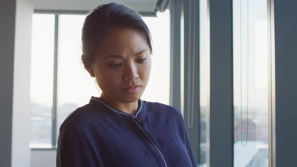 Thoughtful professional businesswoman looking out of a window while her hand on her chin in slow mot