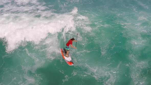 Aerial view of a man sup stand-up paddleboard surfing in Hawaii.