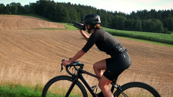 Woman cyclist drinking water during intense endurance cycling training