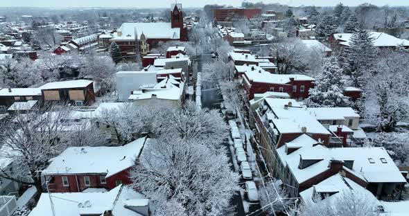 Aerial reveal above street during winter snow. Night shot in evening. Reverse aerial dolly shot.