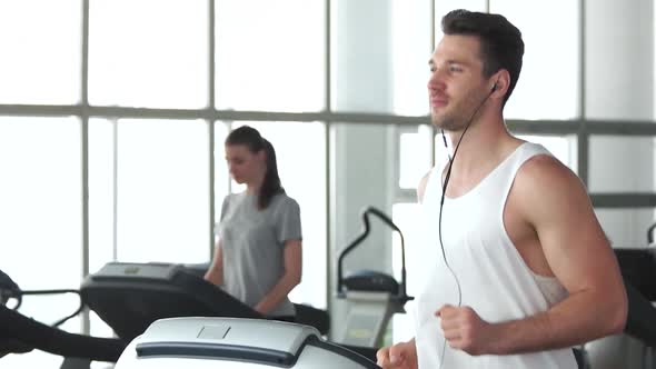 Young Muscular Man Running on Treadmill.