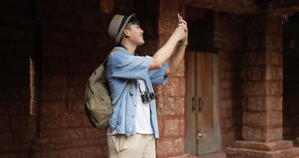 Man takes a photo on smartphone and visits ancient temple