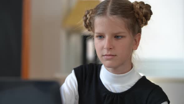 Closeup Portrait of Concentrated Smart Teen Schoolgirl Studying Online