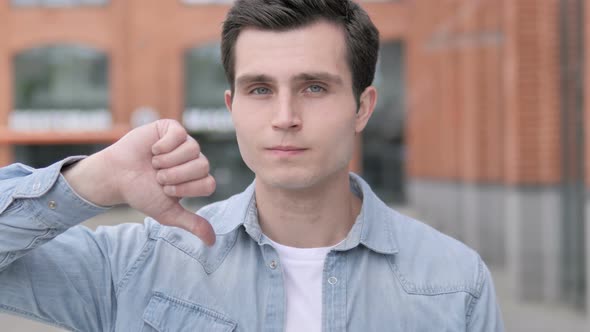 Thumbs Down by Young Man Standing Outdoor