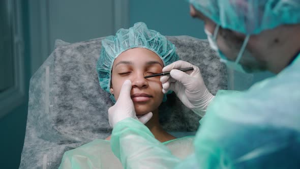 Surgeon Examines Girl's Face Before Rhinoplasty Surgery Drawing on Her Nose