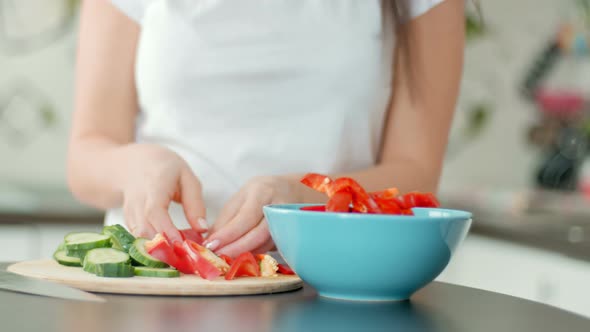 Pretty Young Woman Prepares Lunch and Puts Pepper in Bowl for Salad