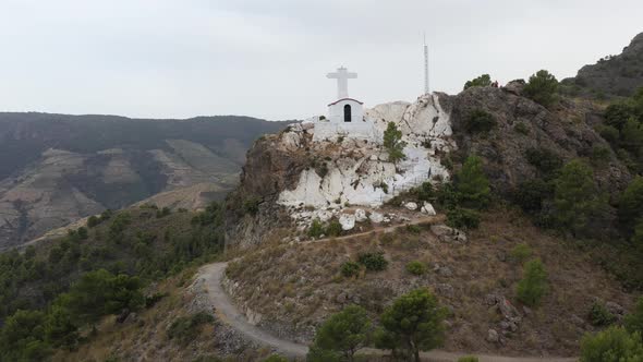 Tourists on a mountain top with tiny white church, Granada, Spain.  Rotating rising drone.
