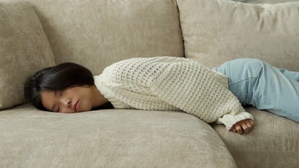 Exhausted Young Asian Woman Falls on the Sofa